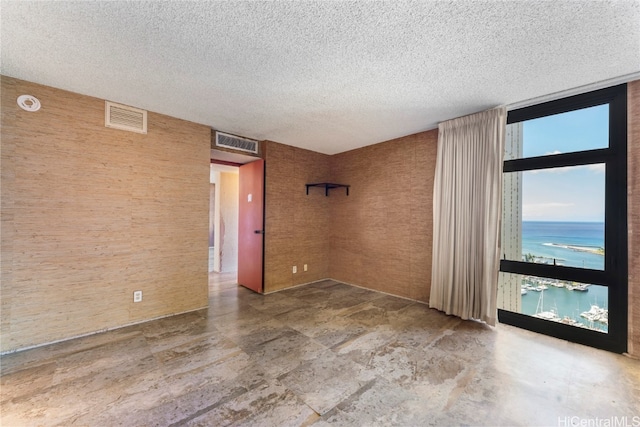 empty room with a textured ceiling and a water view