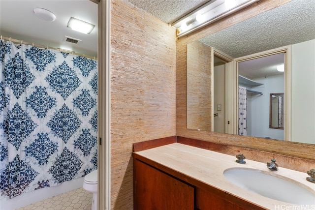 bathroom with toilet, a textured ceiling, vanity, and tile patterned floors