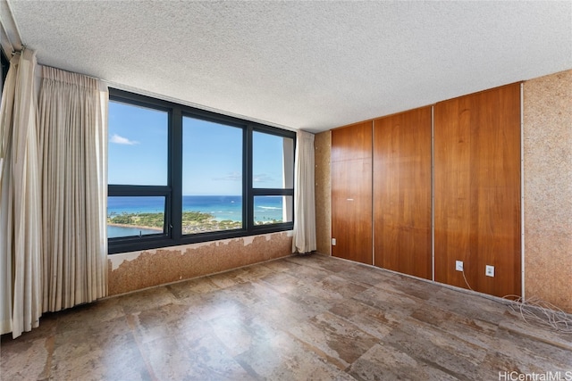 spare room with a textured ceiling and a water view