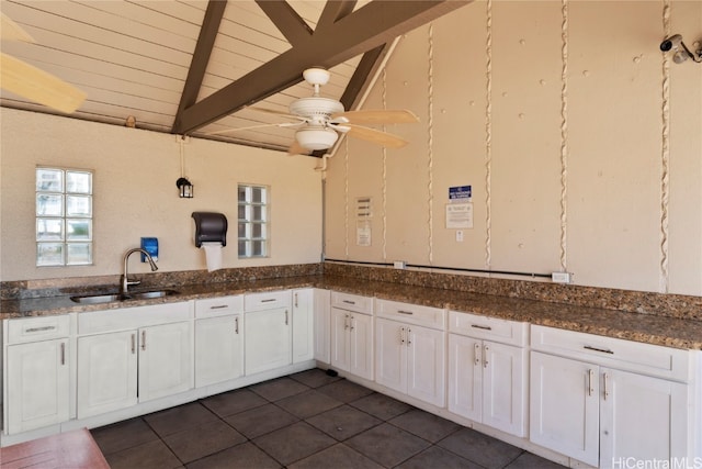 kitchen featuring white cabinets, lofted ceiling with beams, sink, and dark tile patterned floors