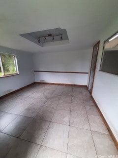 spare room featuring a raised ceiling and light tile patterned floors