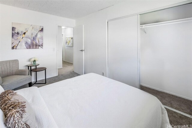 bedroom with a closet, a textured ceiling, and dark colored carpet