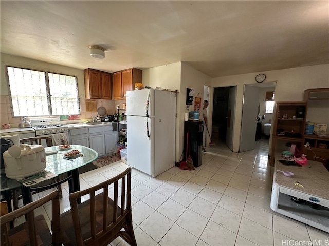 kitchen with sink, light tile patterned flooring, backsplash, gas stove, and white refrigerator