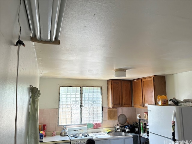 kitchen with white fridge, decorative backsplash, sink, and stove