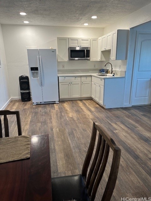 kitchen featuring sink, dark hardwood / wood-style flooring, white refrigerator with ice dispenser, and white cabinets