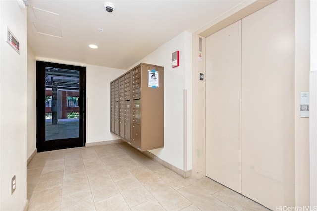 corridor featuring mail boxes, elevator, and light tile patterned floors