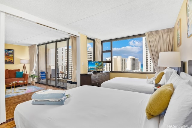 bedroom with hardwood / wood-style floors, a textured ceiling, access to outside, and floor to ceiling windows