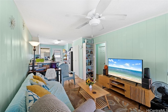 living room featuring wood walls, hardwood / wood-style floors, and ceiling fan