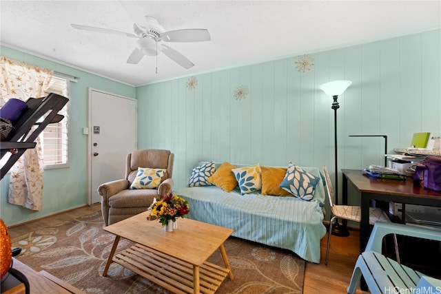 living room with light hardwood / wood-style floors, wooden walls, and ceiling fan