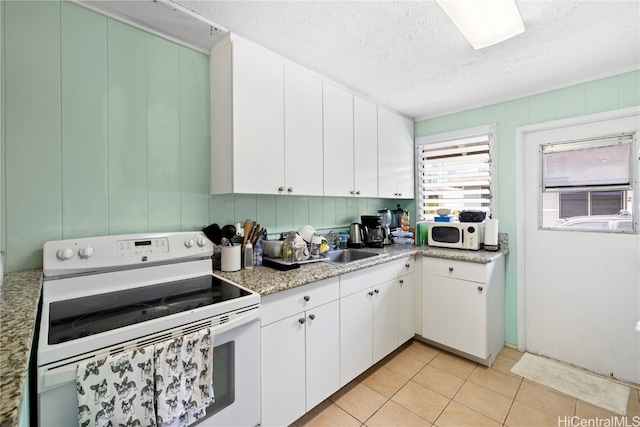 kitchen featuring white appliances, light tile patterned flooring, sink, a textured ceiling, and white cabinetry