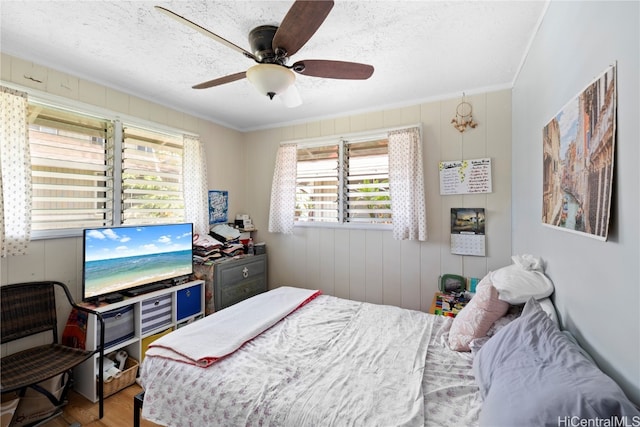 bedroom featuring crown molding, a textured ceiling, hardwood / wood-style flooring, and ceiling fan