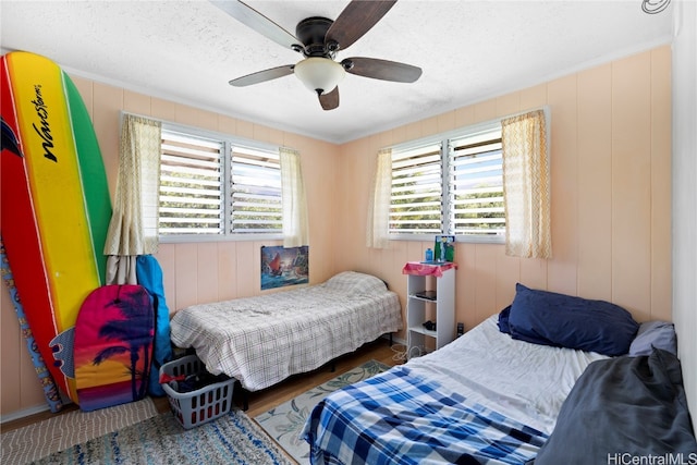 bedroom featuring multiple windows, a textured ceiling, dark wood-type flooring, and ceiling fan