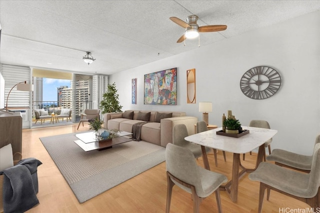 living room with a textured ceiling, hardwood / wood-style flooring, ceiling fan, and a wall of windows