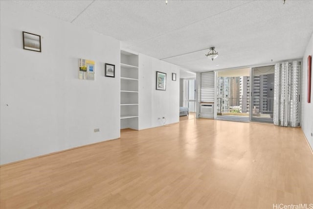 unfurnished living room with a textured ceiling, built in features, and wood finished floors