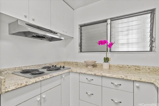 kitchen with white cabinets, under cabinet range hood, stainless steel stovetop, and light countertops