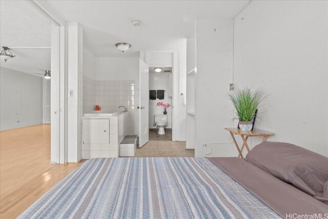 bedroom featuring ensuite bathroom and light wood-type flooring