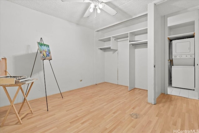 interior space with light hardwood / wood-style flooring, ceiling fan, and stacked washer / drying machine