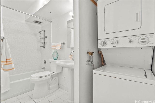 bathroom featuring toilet, shower / bath combo with shower curtain, tile patterned flooring, and stacked washer and dryer