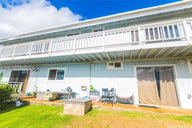 rear view of property featuring a balcony and a lawn