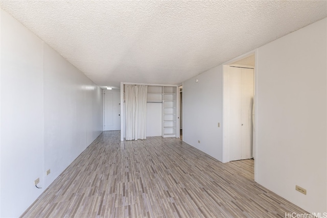 empty room featuring a textured ceiling and light hardwood / wood-style floors