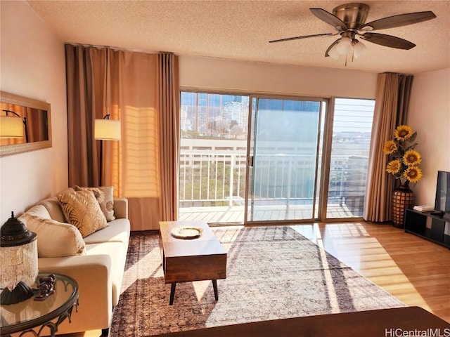 living room with ceiling fan, hardwood / wood-style floors, and a textured ceiling