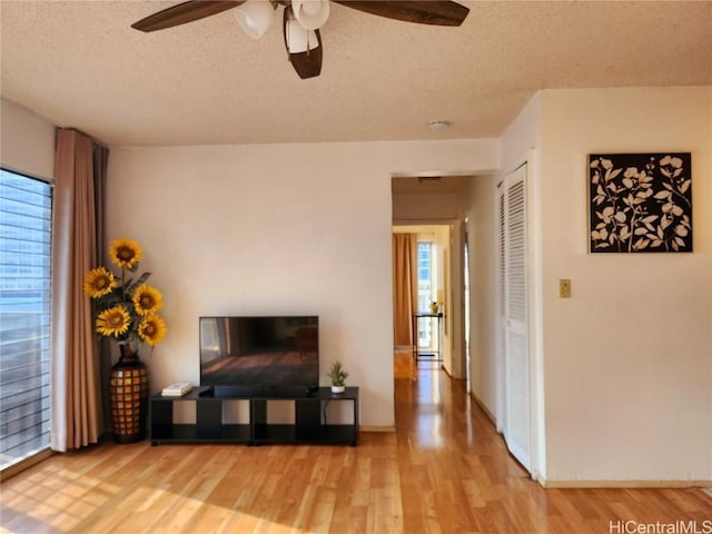 living room with hardwood / wood-style floors, a textured ceiling, and ceiling fan