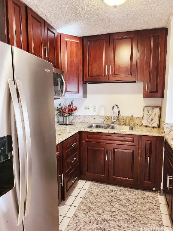 kitchen featuring sink, stainless steel appliances, light stone counters, a textured ceiling, and light tile patterned floors