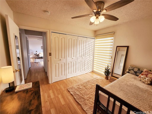 bedroom featuring a textured ceiling, a closet, ceiling fan, and light hardwood / wood-style floors