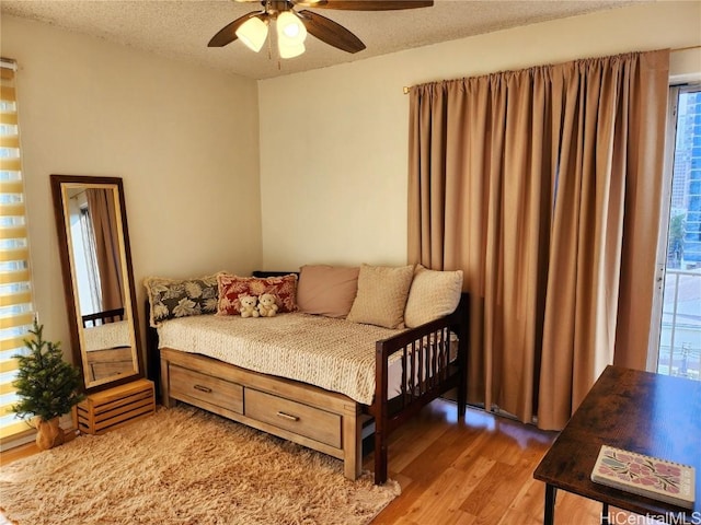 bedroom with ceiling fan, a textured ceiling, and hardwood / wood-style flooring