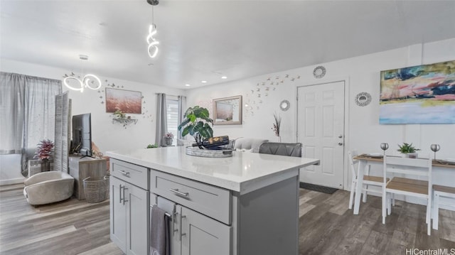 kitchen with gray cabinets, a kitchen island, hanging light fixtures, and dark hardwood / wood-style floors