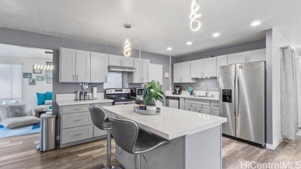 kitchen featuring wood-type flooring, appliances with stainless steel finishes, sink, and decorative light fixtures