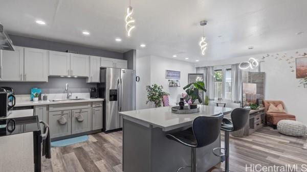 kitchen with black electric range oven, sink, decorative light fixtures, and stainless steel fridge with ice dispenser