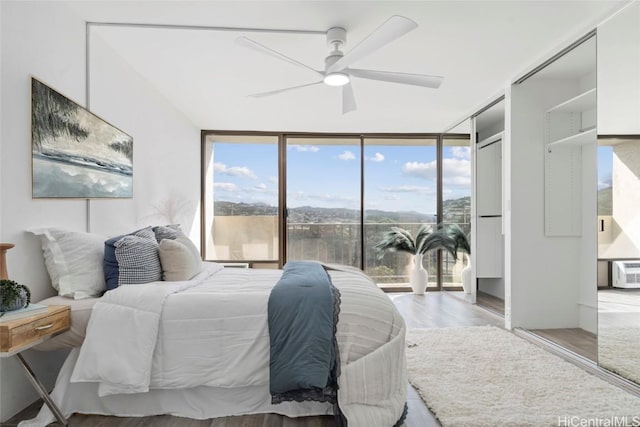 bedroom featuring ceiling fan, expansive windows, and light hardwood / wood-style floors