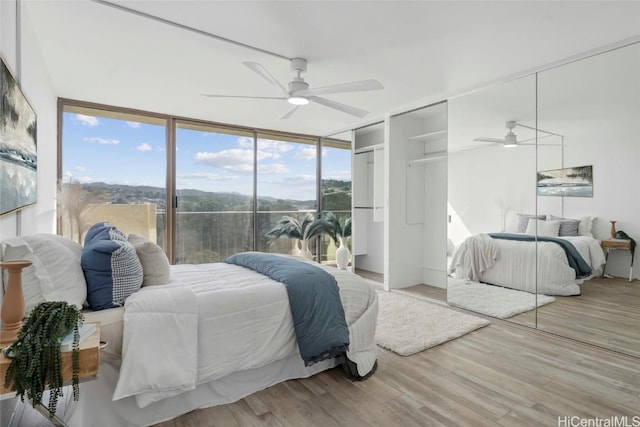 bedroom featuring ceiling fan, a wall of windows, and light wood-type flooring