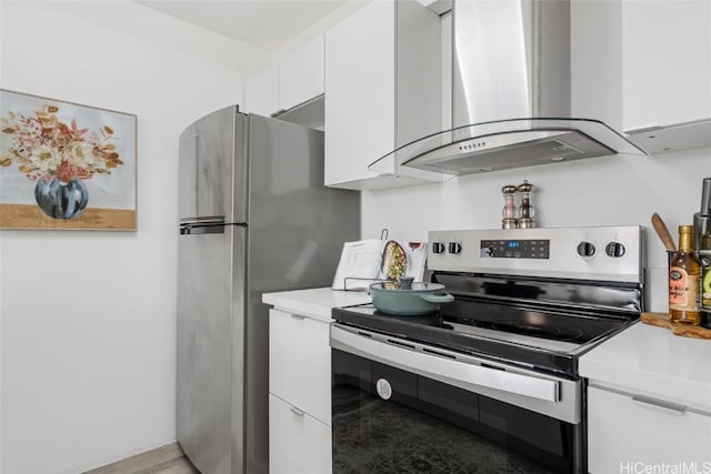 kitchen with white cabinetry, light wood-type flooring, wall chimney range hood, and stainless steel appliances