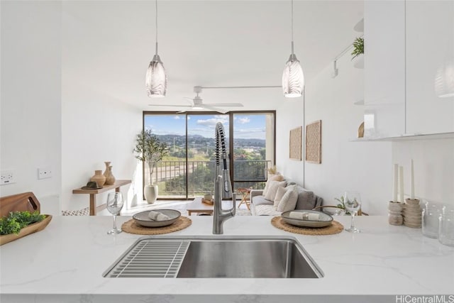 kitchen featuring light stone counters, sink, and decorative light fixtures