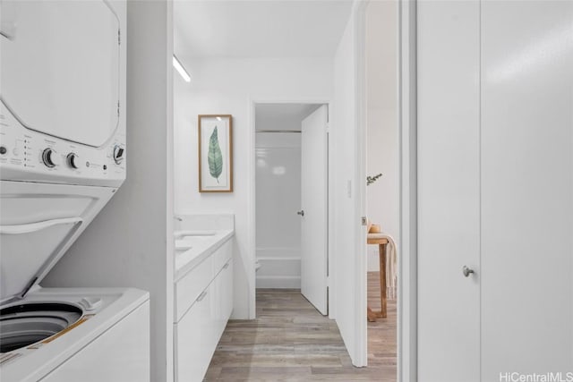 laundry room with light wood-type flooring and stacked washer and dryer