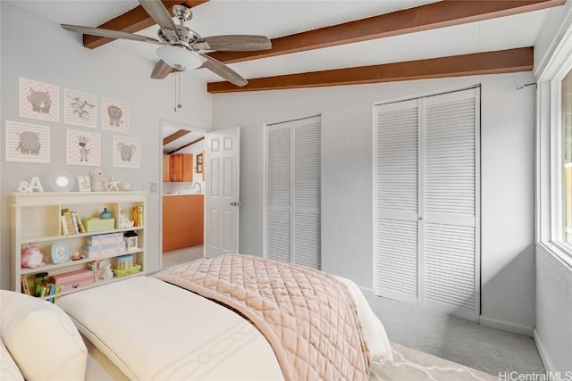 carpeted bedroom featuring ceiling fan, lofted ceiling with beams, and multiple closets