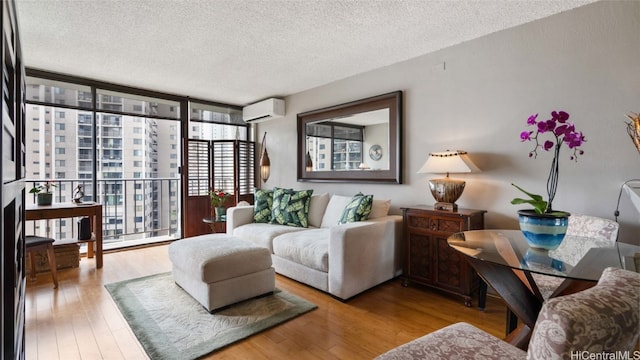 living room featuring an AC wall unit, a textured ceiling, and hardwood / wood-style flooring