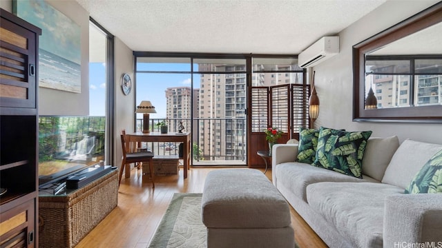 living room featuring expansive windows, light hardwood / wood-style flooring, a textured ceiling, and an AC wall unit