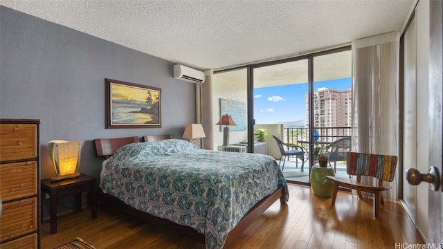 bedroom with access to outside, an AC wall unit, a textured ceiling, hardwood / wood-style floors, and a wall of windows