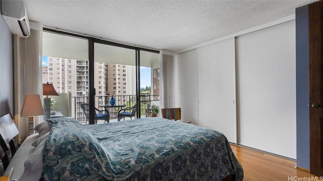 bedroom with a closet, hardwood / wood-style flooring, a textured ceiling, and floor to ceiling windows