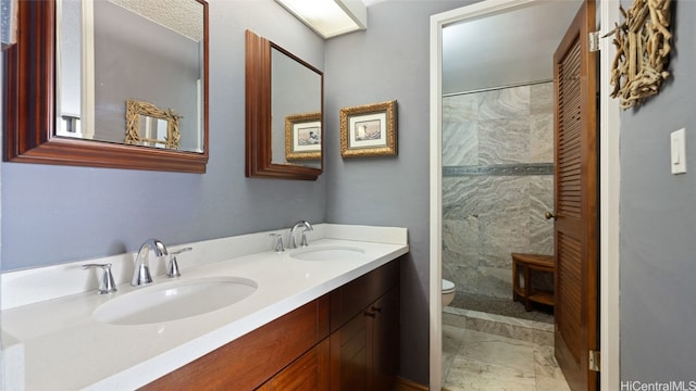 bathroom with toilet, vanity, and a tile shower