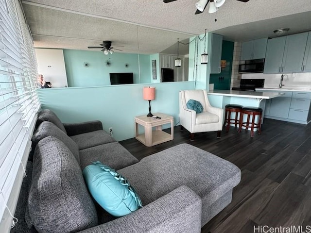 living room featuring dark wood-style floors, a textured ceiling, and ceiling fan