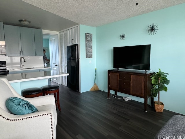 kitchen with black appliances, sink, a kitchen bar, a textured ceiling, and dark hardwood / wood-style flooring