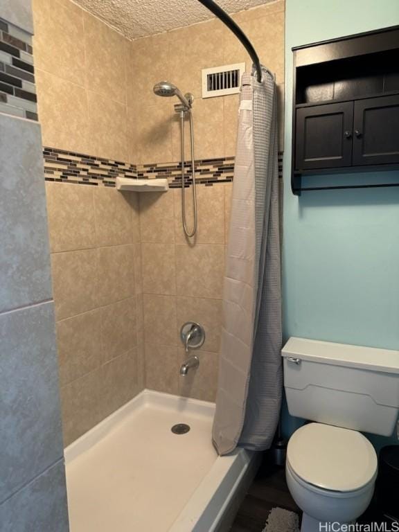 bathroom featuring toilet, a shower with curtain, and visible vents