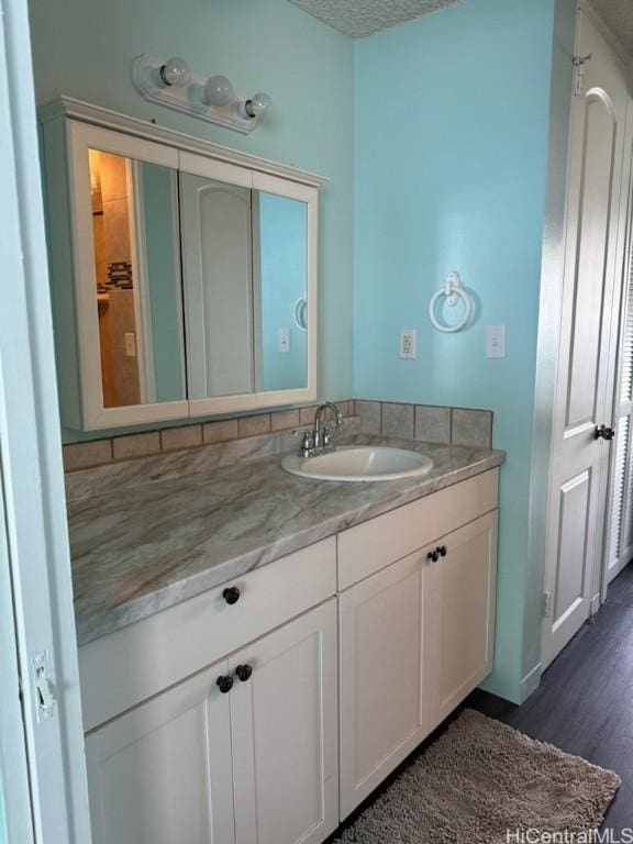 bathroom featuring vanity, wood finished floors, and a textured ceiling