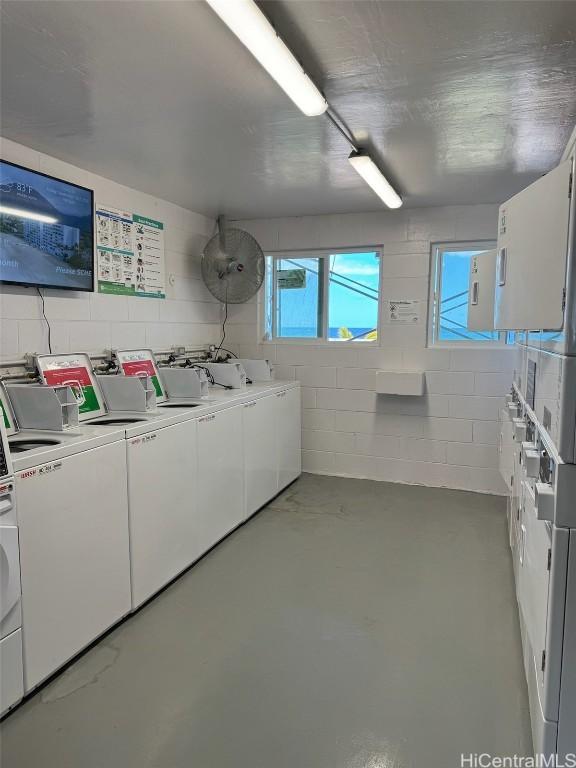 shared laundry area featuring stacked washer and dryer, concrete block wall, and separate washer and dryer