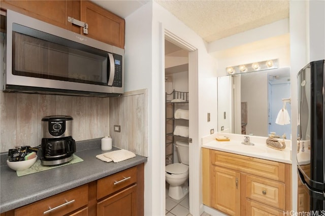 bathroom featuring tile patterned floors, vanity, toilet, and a textured ceiling