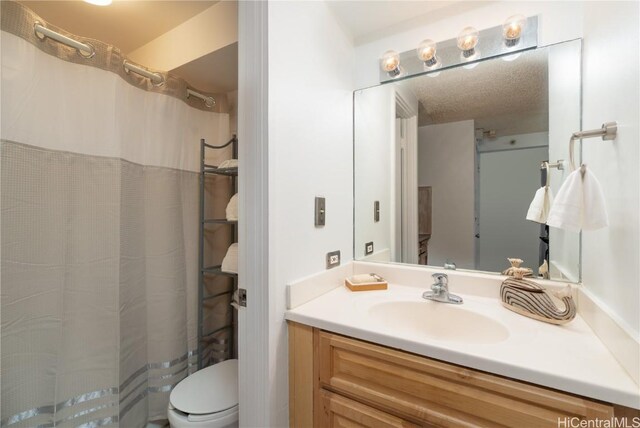 bathroom featuring vanity, a textured ceiling, and toilet